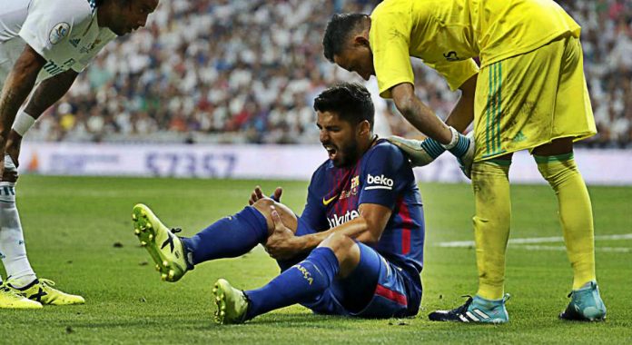 Luis Suarez clutches his right knee in pain during Barcelona’s defeat to Real Madrid